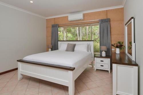 a bedroom with a white bed and white walls at Eight Willows Retreat in Margaret River Town