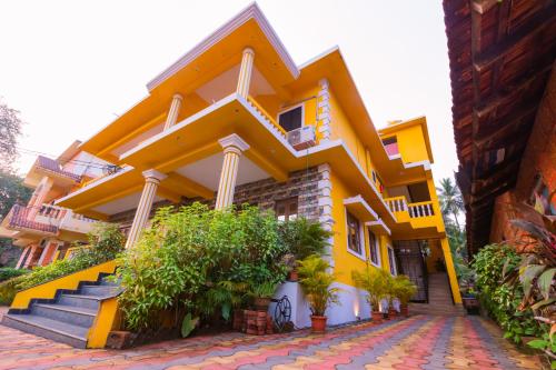 um edifício amarelo com escadas e plantas em frente em PINNACLE MIST , CALANGUTE BEACH ROAD em Calangute