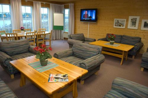 uma sala de espera com sofás e mesas e uma televisão em Brovillan em Lekeryd