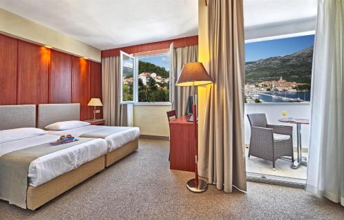 a bedroom with a bed and a balcony with a view at Marko Polo Hotel by Aminess in Korčula