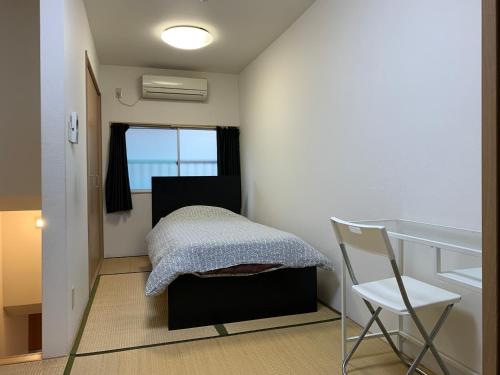 - une petite chambre avec un lit et une chaise dans l'établissement EX2 Higashimikuni Hous, à Osaka