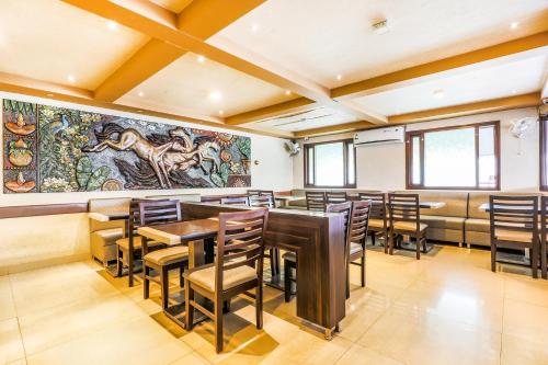 a dining room with tables and chairs and a large mural at FabHotel Sri Krishna Suites Bellandur in Bangalore