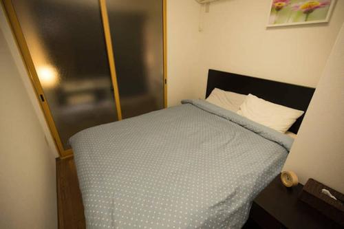 a bedroom with a bed with a blue comforter at EX2 Higashimikuni Hous in Osaka