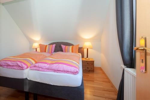 Auszeit auf Rügen في Nardevitz: سرير مع بطانيات ووسائد ملونة في الغرفة