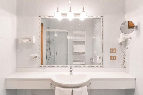 Hotel Bauhof في كاستلبيلو: حمام أبيض مع حوض ومرآة