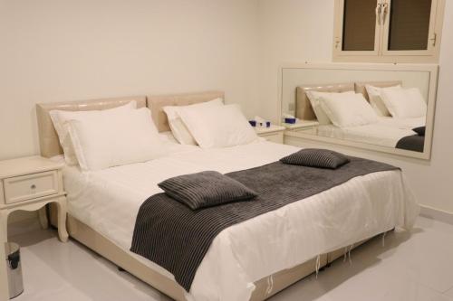 a bedroom with two beds with white sheets and a mirror at بيت السليمي التراثي in Shaqra