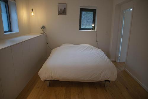 um pequeno quarto com uma cama com um cobertor branco em Le Moulin de Bosson - Belina em Ferrières