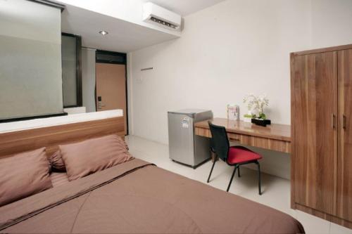 ein Schlafzimmer mit einem Bett, einem Schreibtisch und einem Stuhl in der Unterkunft D'Paragon Seturan 3 in Yogyakarta