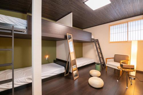 Zimmer mit 2 Etagenbetten und einem Stuhl in der Unterkunft Tsumugian in Housai