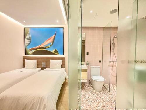 two beds in a hotel room with a bathroom at L Hotel at Bugis Ville in Singapore