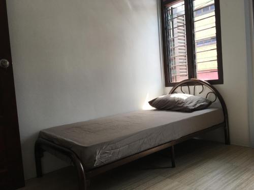 a small bed in a room with a window at Homey Hostel, Ipoh Town in Ipoh