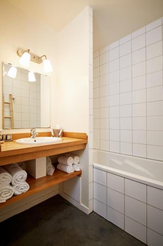 une salle de bain avec un lavabo, une baignoire et un miroir dans l'établissement Hotel La Maison de la Prade, à Messanges