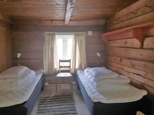 two beds in a wooden room with a window at Lensmansgarden Marteinsgarden in Innfjorden