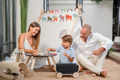 a family playing with a toy table with a laptop at Anantara Lawana Koh Samui Resort in Chaweng