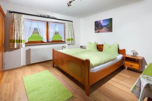 a bedroom with a bed with green sheets and a window at Gästehaus Untersulzberglehen in Schönau am Königssee