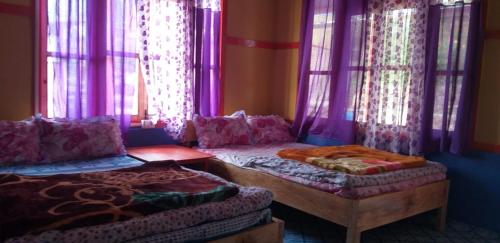 a room with two beds and purple curtains at Vamoose Niru in Pedong