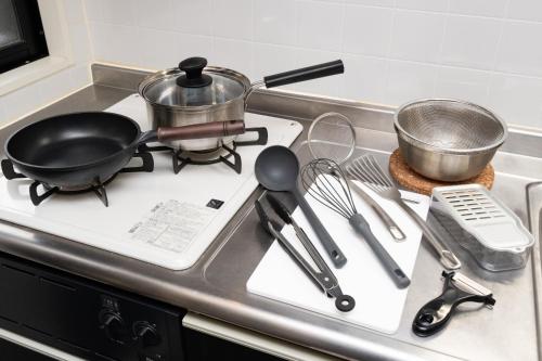 a kitchen stove with a frying pan and utensils on it at ローズパーク弐番館 in Funabashi