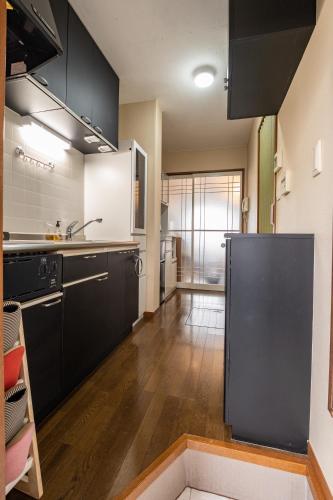 a kitchen with black cabinets and wooden floors at ローズパーク弐番館 in Funabashi