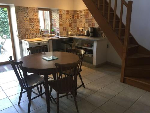 una cocina con mesa y sillas y una escalera en Les chambres d'hôtes de l'Ecurie Goupil en Mont-le-Vignoble