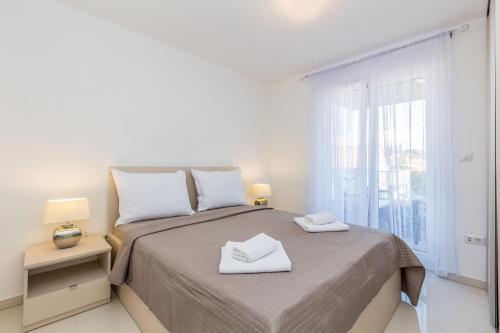 biała sypialnia z łóżkiem z 2 ręcznikami w obiekcie Apartment LAGANINI III w mieście Nijvice