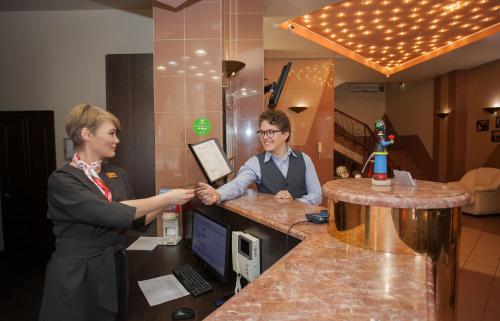 a woman and a man are looking at a laptop at Hotel Khakasia in Abakan