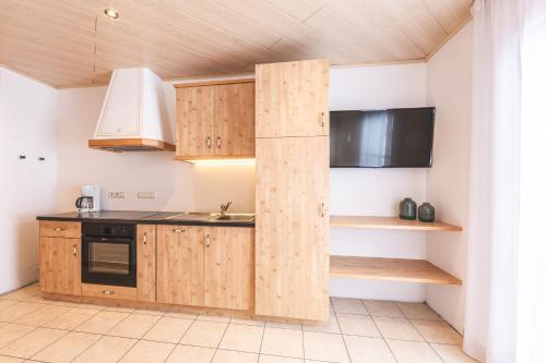 a kitchen with wooden cabinets and a microwave at Residence Alpina in Santa Maddalena in Casies