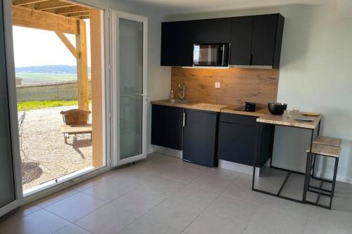 a kitchen with black cabinets and a view of a patio at Studio indépendant au calme avec vue imprenable in Bossieu