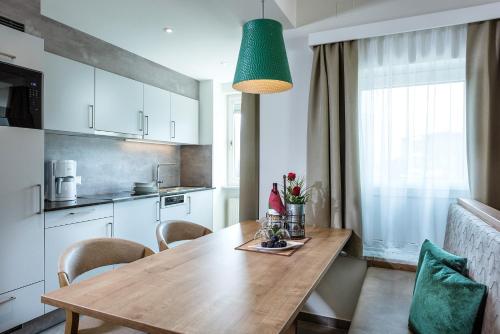 a kitchen with a wooden table and a green lamp at Aktiv- & Gesundheitsresort das GXUND - Thermeneintritt inklusive in Bad Hofgastein