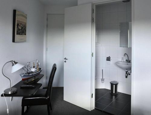uma casa de banho com uma mesa, um lavatório e uma porta branca em Hotel Royal em IJmuiden