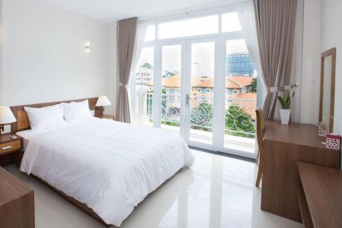 a bedroom with a white bed and a large window at Khanh Gia Apartment in Ho Chi Minh City