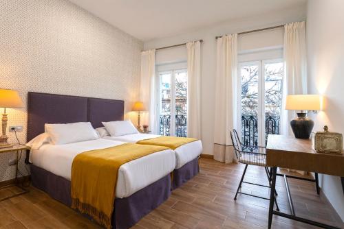 ein Schlafzimmer mit einem großen Bett und zwei Fenstern in der Unterkunft Genteel Home Recaredo in Sevilla