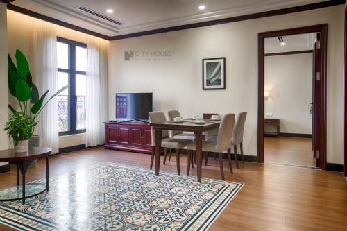 a dining room with a table and chairs and a television at CityHouse - Atelier Apartment & Hotel in Ho Chi Minh City
