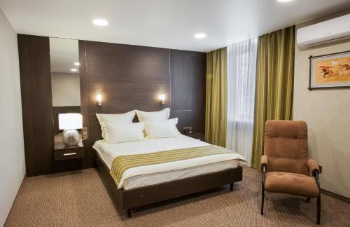a hotel room with a bed, chair, and nightstand at Hotel Khakasia in Abakan