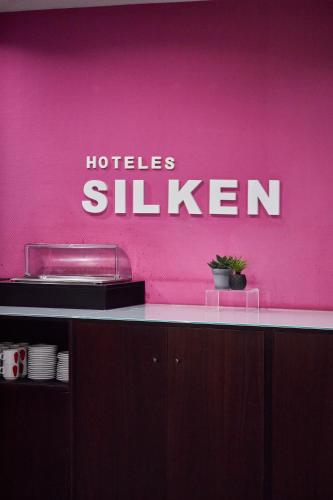 a pink wall with the words holles sluzen on it at Silken Rona Dalba in Salamanca