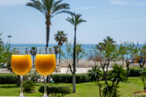 dos copas de vino sentadas en una mesa con palmeras en Garden & Beach - Torremolinos en Torremolinos