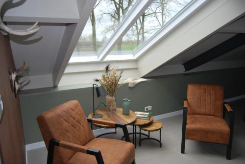 a attic room with a table and two chairs at Hoeve de Heemser Parel in Heemserveen