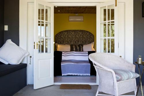 a porch with a bed and a wicker chair at Olive Grove Pip in Prince Albert