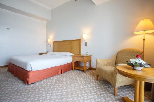 a hotel room with a bed and a table and chairs at The Linden Suites in Manila