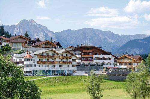 een groep gebouwen op een heuvel met bergen op de achtergrond bij Mountains Hotel in Seefeld in Tirol