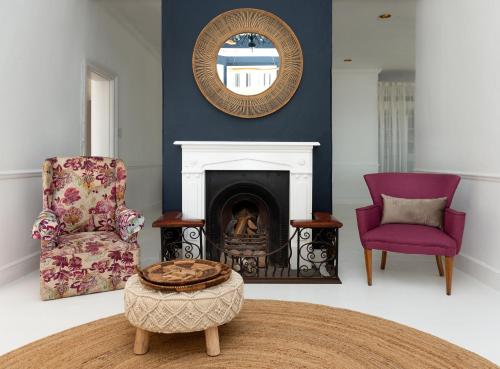 a living room with two chairs and a fireplace at Boulders Beach Hotel, Cafe and Curio shop in Simonʼs Town