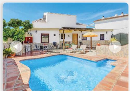 a villa with a swimming pool in front of a house at Villa Damara con piscina privada in Nerja