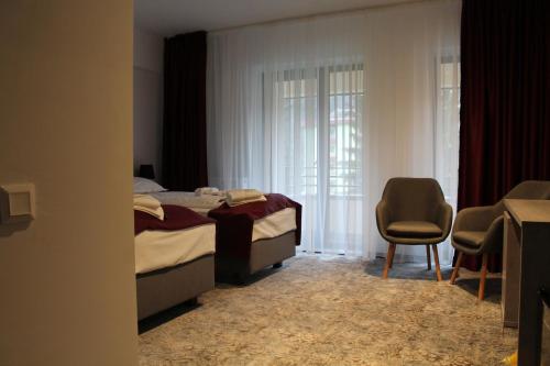 ein Schlafzimmer mit einem Bett, einem Stuhl und einem Fenster in der Unterkunft Hotel Parang in Băile Olăneşti