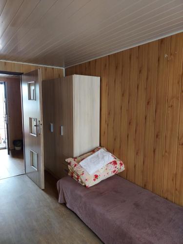 Cama en habitación con pared de madera en Leśny dworek - pokoje nad jeziorem en Koczała