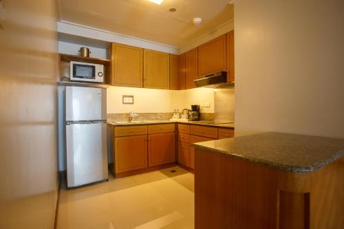 a kitchen with wooden cabinets and a white refrigerator at The Linden Suites in Manila