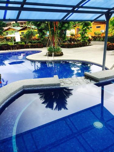 a swimming pool with an umbrella and blue water at Hotel Villas Vilma in Fortuna