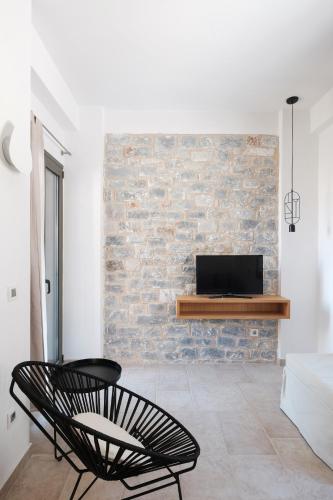 a black chair in a living room with a brick wall at Margo Beach Hotel in Gythio