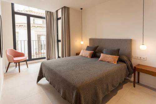a bedroom with a bed and a chair and a window at Apartamentos Málaga Premium - Calle Granada in Málaga