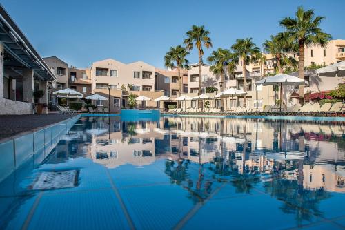 Una gran piscina con palmeras y edificios. en Stellina Village, en Kato Daratso