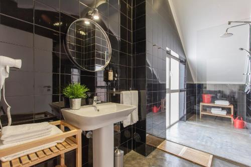 ein schwarz gefliestes Bad mit einem Waschbecken und einer Dusche in der Unterkunft Emporium Lisbon Suites in Lissabon