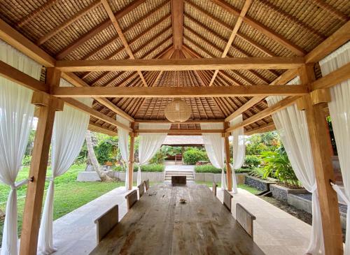 an open pavilion with white curtains and a wooden ceiling at Gayatri in Ubud